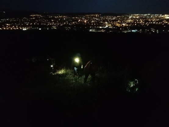 Lumières de cyclistes montant (à pied !) un chemin dans la nuit noire. Lumières de Clermont-Ferrand en arrière plan