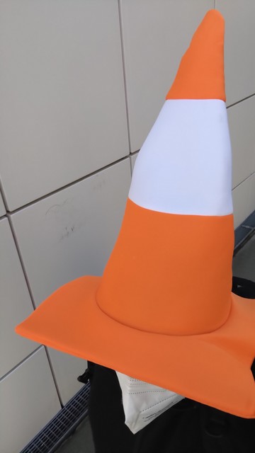 Une personne avec un chapeau en forme de cône de chantier en mousse aux couleurs orange et blanche 