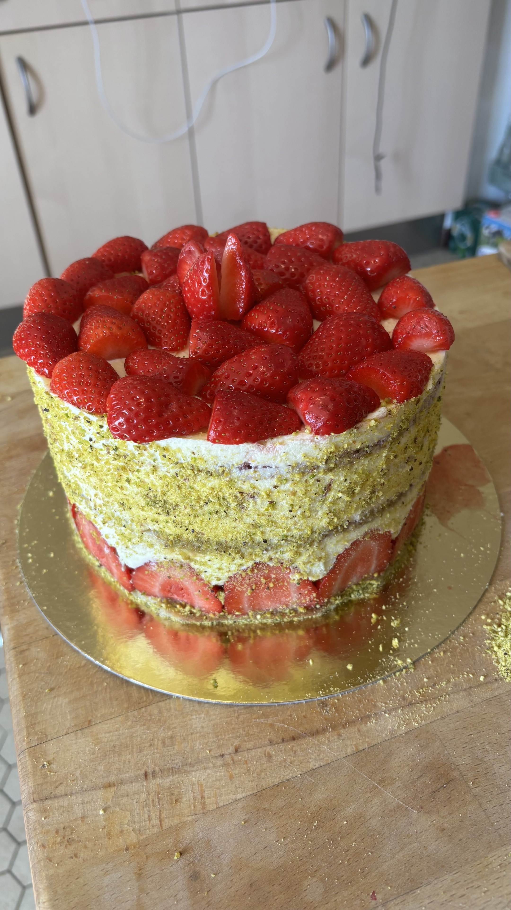 Le fraisier terminé, les cotés sont décoré de poudre de pistache et le dessus couvert de fraises.