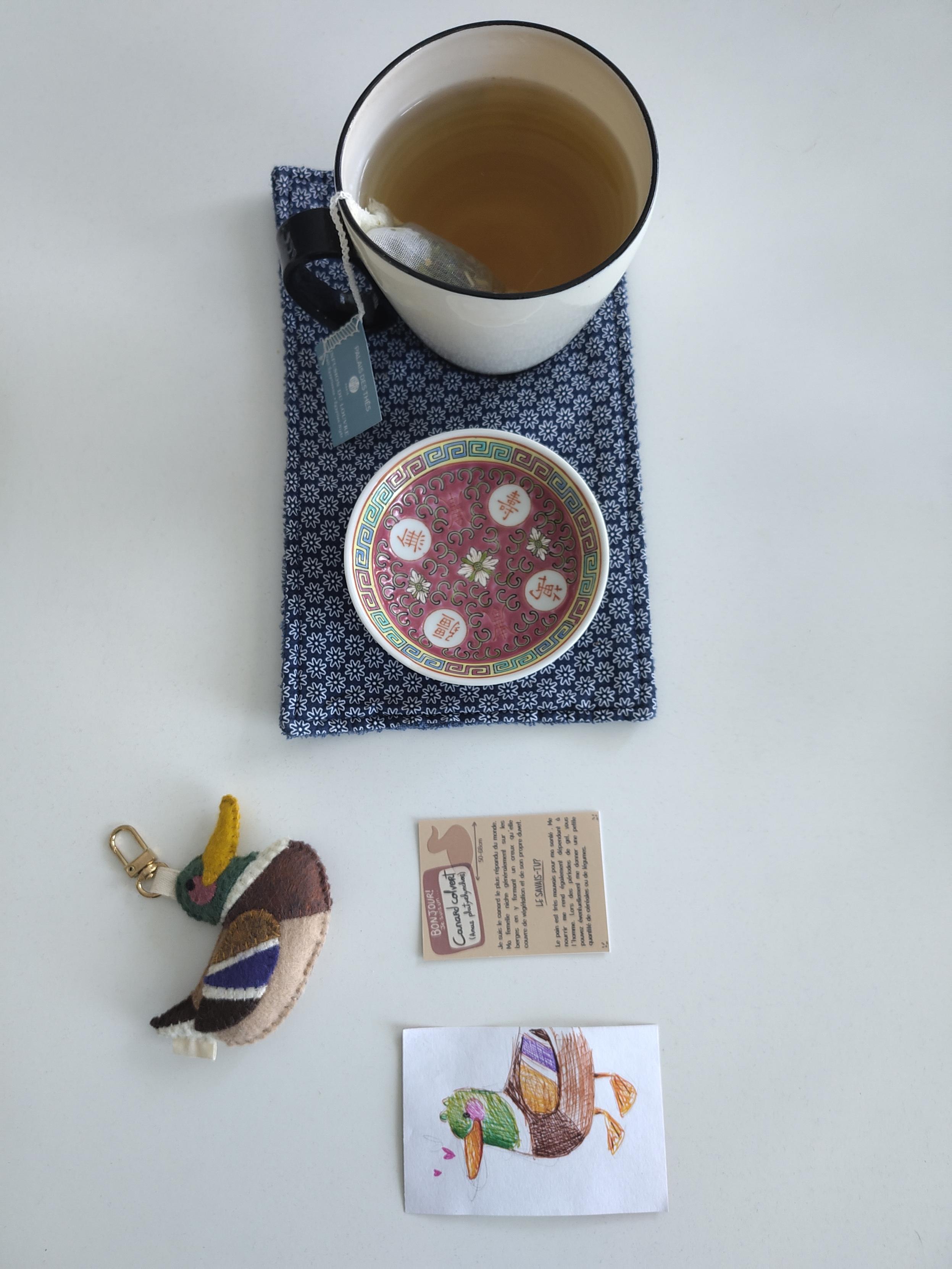 Vue du dessus. Tasse de thé, note explicative, peluche en feutre de canard colvert et dessin très mignon de canard colvert